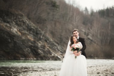 Mutlu evlilik çift, gelin ve damat zemin Dağları nın karşı temiz nehir poz