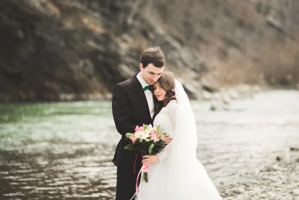 Mutlu evlilik çift, gelin ve damat zemin Dağları nın karşı temiz nehir poz — Stok fotoğraf
