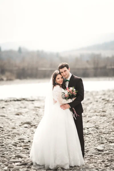 Bellissimo matrimonio coppia baciare e abbracciare vicino al fiume con pietre — Foto Stock