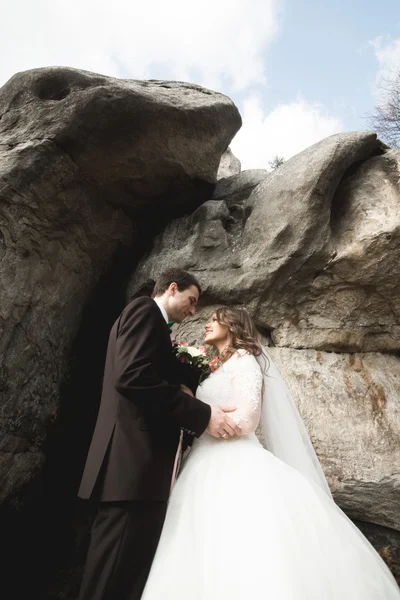 Šťastný Svatební pár líbání a objímání poblíž vysokého útesu — Stock fotografie