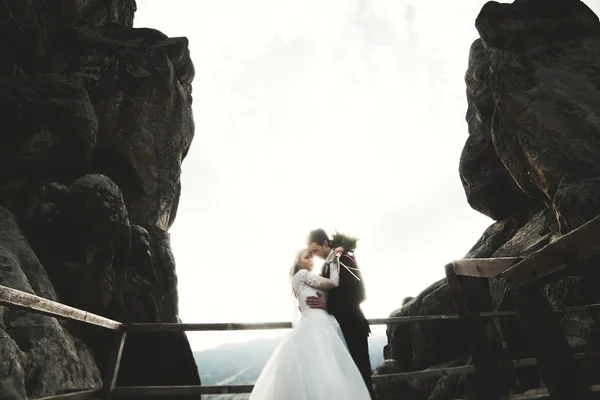 Счастливая супружеская пара, невеста и жених позируют возле скал с прекрасным видом — стоковое фото