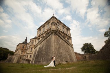 Güzel, romantik bir düğün. Yeni evliler. Eski kalenin yakınlarında sarılıyorlar.