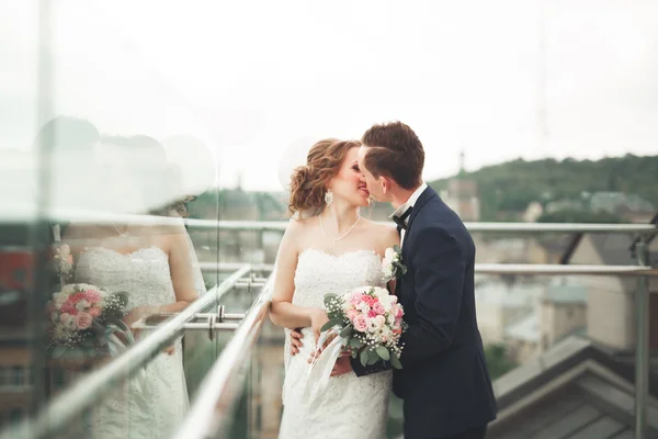 Krásný pár, nevěsta a ženich pózuje na balkoně s backgrounf staré město — Stock fotografie