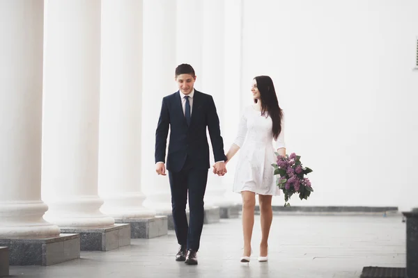 Hermosa pareja, novia y novio posando cerca de gran columna blanca — Foto de Stock