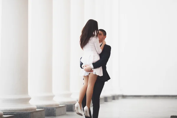 Hermosa pareja, novia y novio posando cerca de gran columna blanca — Foto de Stock