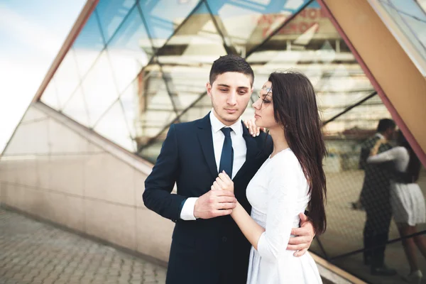 Elegante casal amoroso beijando e abraçando perto de edifício moderno — Fotografia de Stock