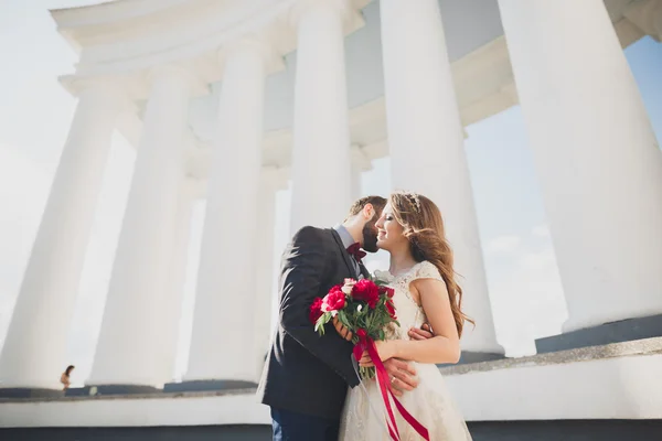 Prachtige paar, bruid en bruidegom poseren in de buurt van grote witte kolom — Stockfoto
