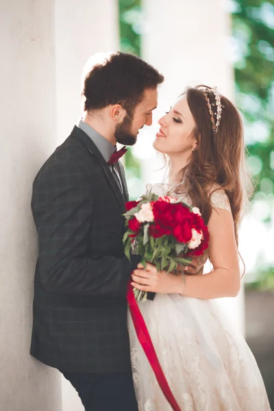 Beautiful couple, bride and groom posing near big white column — Stock Photo, Image