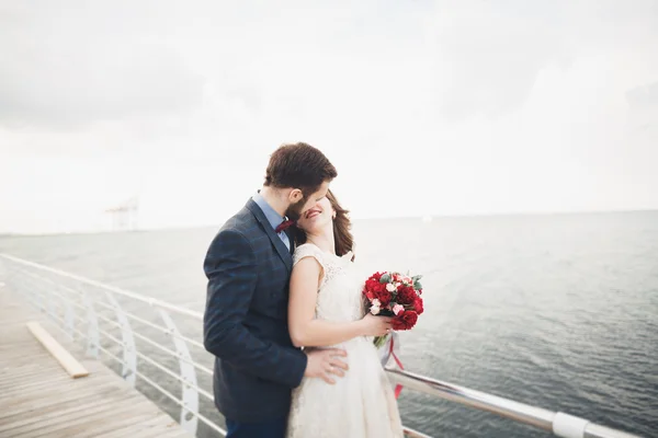 Casamento casal em pé em um cais sobre o mar — Fotografia de Stock