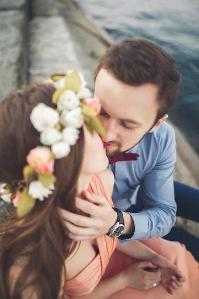 結婚式のカップルの青い海とその周辺の大きな石の上に座って — ストック写真