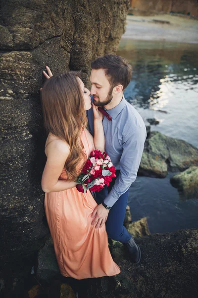 Casamento casal sentado em pedra grande em torno do mar azul — Fotografia de Stock