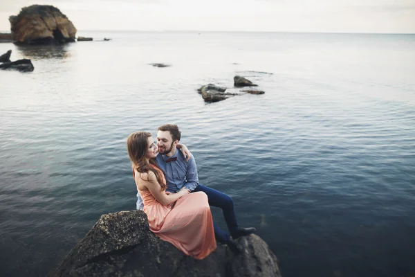 Весільна пара цілується і обіймається на каменях біля блакитного моря — стокове фото