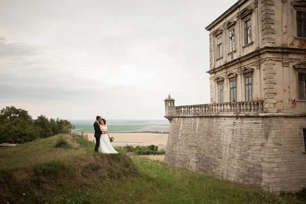 Feliz casamento casal abraçando e beijando no fundo velho castelo — Fotografia de Stock