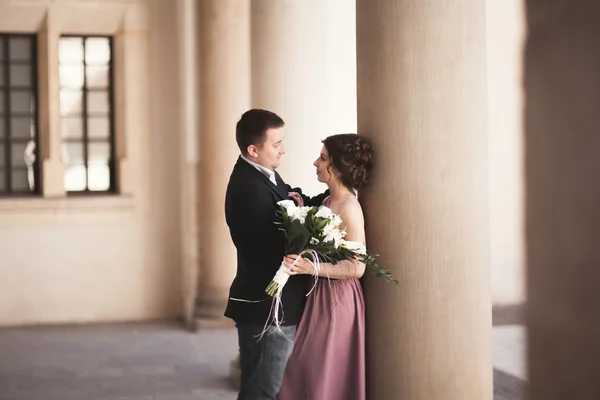 Gelukkig huwelijk bruidegom, paar, bruid met roze jurk knuffelen en glimlachen elkaar op de achtergrond muren in kasteel — Stockfoto