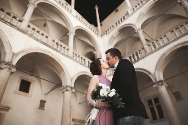 Hermosa pareja, hombre, chica con vestido largo de color rosa posando en el viejo castillo cerca de columnas. Cracovia Vavel — Foto de Stock