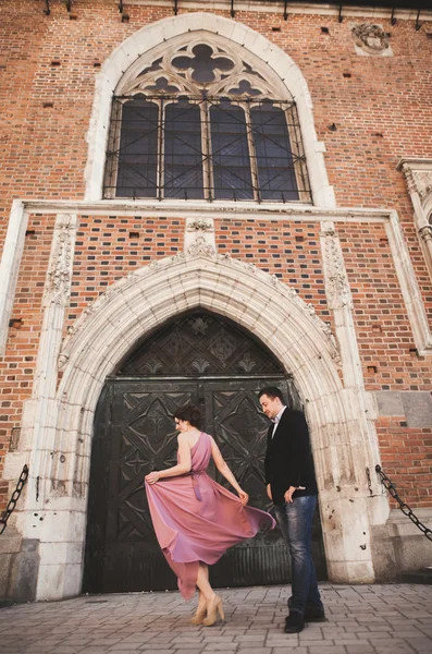 豪華な結婚式のカップルは新郎、クラクフの旧市街に歩いてピンクのドレスと花嫁 — ストック写真