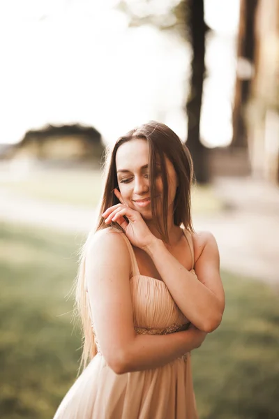 Attraente giovane donna con abito lungo godendo il suo tempo fuori nel parco sfondo tramonto — Foto Stock