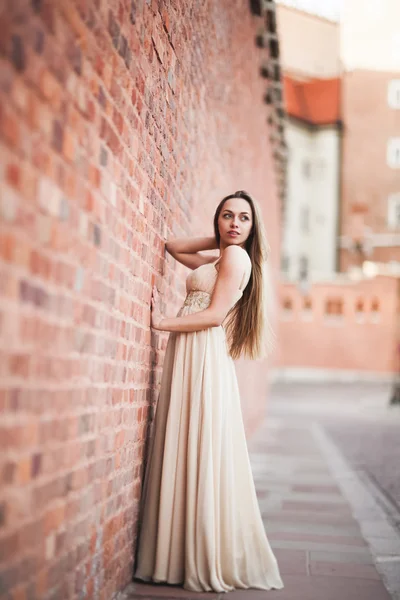Красивая сексуальная девушка с длинными волосами и платье идеальной формы загорелое тело, имеющее около стены — стоковое фото