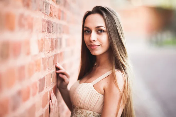 Schöne sexy Mädchen mit langen Haaren und Kleid perfekte Form gebräunten Körper posiert in der Nähe der Wand — Stockfoto