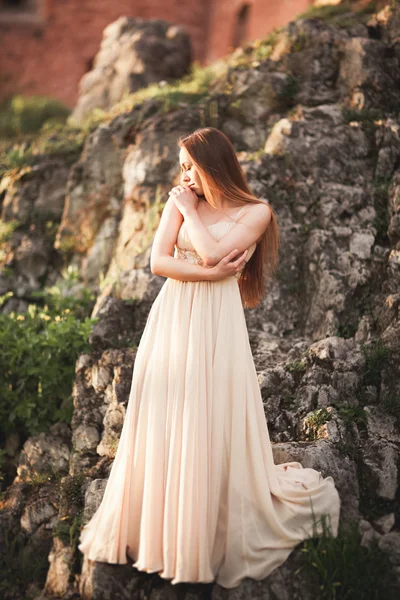 Attraktiv ung kvinna i lång klänning står på klipporna — Stockfoto
