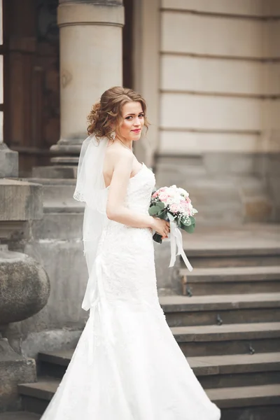 Maravillosa novia con un lujoso vestido blanco posando en el casco antiguo —  Fotos de Stock