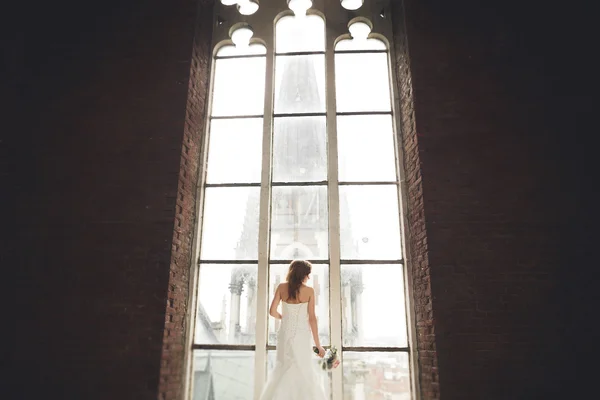Elegante bella sposa nuziale posa vicino grande arco della finestra — Foto Stock