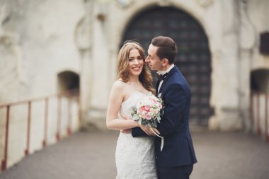 Güzel, romantik bir düğün. Yeni evliler. Eski kalenin yakınlarında sarılıyorlar.