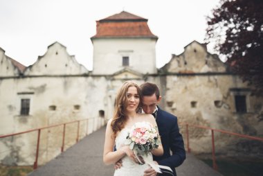 Güzel, romantik bir düğün. Yeni evliler. Eski kalenin yakınlarında sarılıyorlar.