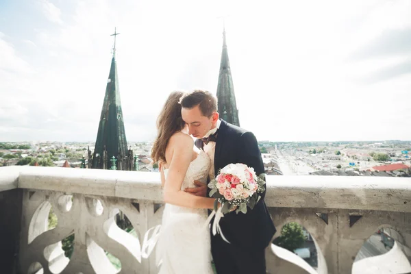 Стильна красива весільна пара цілується і обіймається на фоні панорамного вигляду старого міста — стокове фото