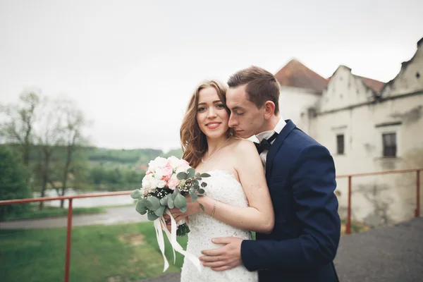 Feliz casamento casal abraçando e sorrindo uns aos outros no fundo velho castelo — Fotografia de Stock