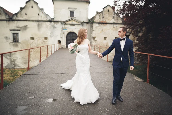 Feliz casamento casal abraçando e sorrindo uns aos outros no fundo velho castelo — Fotografia de Stock