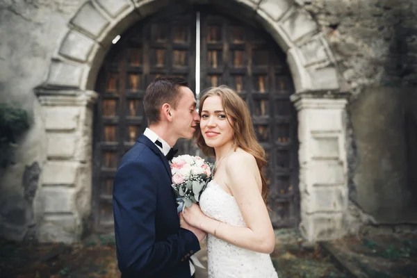 Feliz casamento casal abraçando e sorrindo uns aos outros no fundo velho castelo — Fotografia de Stock