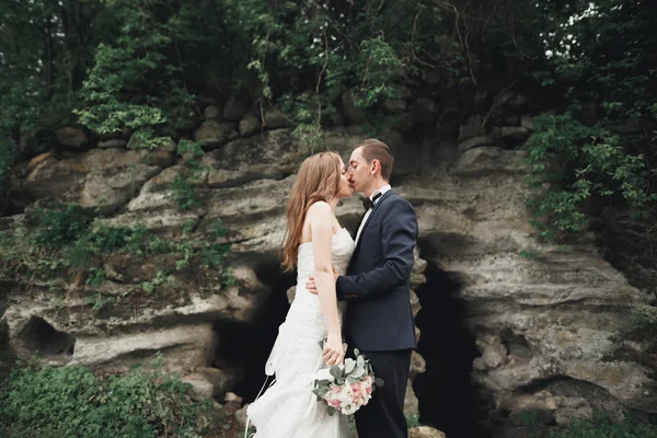 Glückliches Hochzeitspaar umarmt und lächelnd einander auf dem Hintergrund herrliche Pflanzen im Schloss — Stockfoto