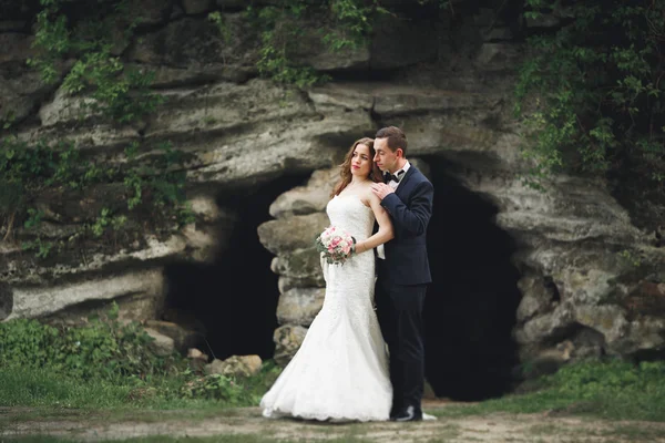 Feliz boda pareja abrazándose y sonriendo el uno al otro en el fondo hermosas plantas en el castillo —  Fotos de Stock