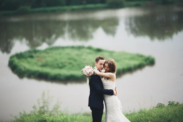 Bellissimo matrimonio coppia baciare e abbracciare vicino lago con isola — Foto Stock