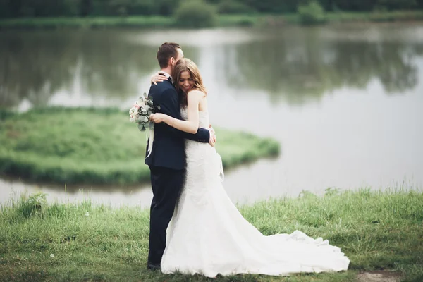 Romantikus esküvő házaspár, a férj és a feleség, pózol, gyönyörű tó közelében — Stock Fotó