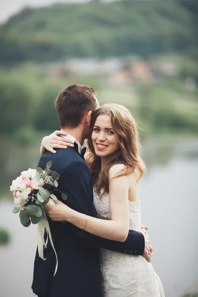 Piękne wesele para całuje i obejmując w pobliżu jezioro z wyspą — Zdjęcie stockowe