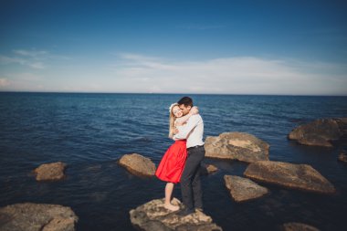 Deniz, mavi gökyüzü yakınındaki taş poz romantik sevgi dolu Çift