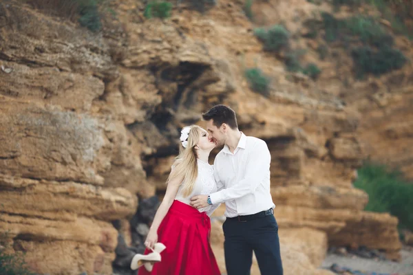 Romantica coppia amorevole a piedi sulla spiaggia con rocce e pietre — Foto Stock