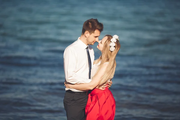 Fiatal, boldog pár séta a tengerparton mosolyogva gazdaság egymás körül. Szerelmi történet — Stock Fotó