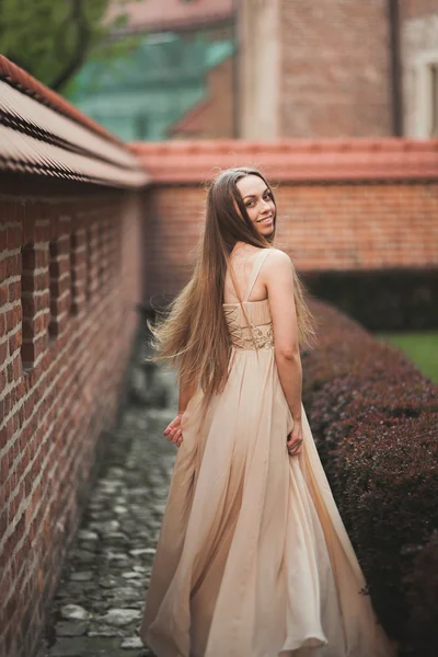 Hermosa chica sexy con el pelo largo y vestido de la forma perfecta cuerpo bronceado possing cerca de la pared — Foto de Stock