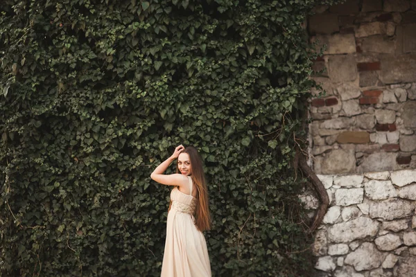 Hermosa chica, modelo cerca de la pared de hojas y arbustos en el parque — Foto de Stock