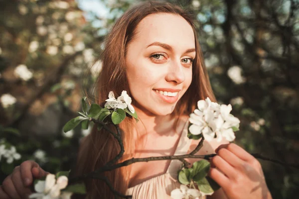 Junges schönes Mädchen in einem langen Kleid und einem Blumenkranz in der Nähe des Fliederstrauches — Stockfoto