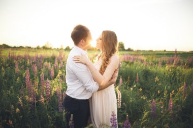 Gelin ve damat, çiçekler, güzel bir alanda gün batımında rissing romantik evli çift