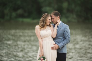 Düğün çift, Gelin, damat öpüşme ve lake yakınındaki köprüde poz güzel