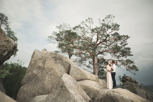 Boda pareja enamorada besándose y abrazándose cerca de rocas en hermoso paisaje — Foto de Stock