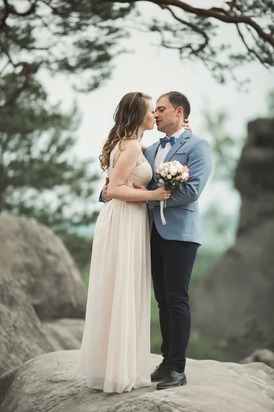 Boda pareja enamorada besándose y abrazándose cerca de rocas en hermoso paisaje — Foto de Stock