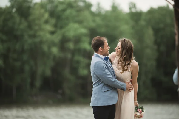 Groom carrying bride near lake and forest — Stock Photo, Image