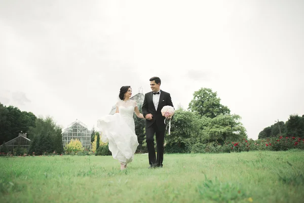 Yeni evli çift el ele tutuşurken parkta koşup zıplıyorlar. — Stok fotoğraf
