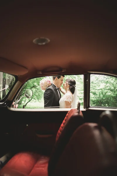 Beautiful wedding couple posing near splendid retro car — Stock Photo, Image